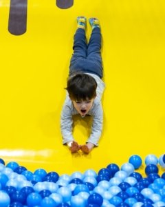 boy sliding into ball pit