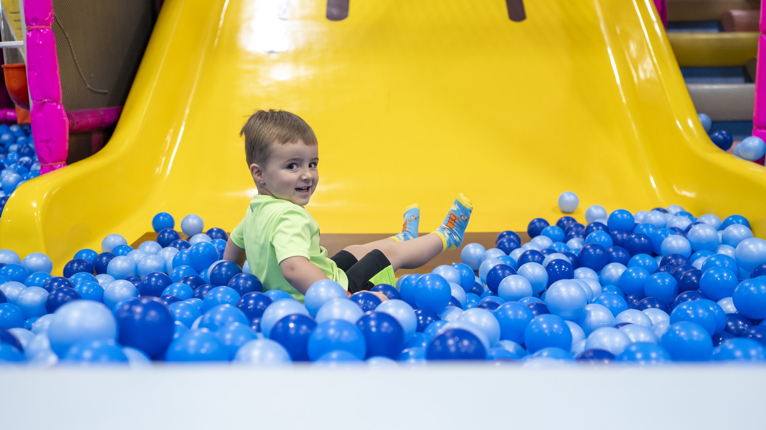 boy sliding into ball pit